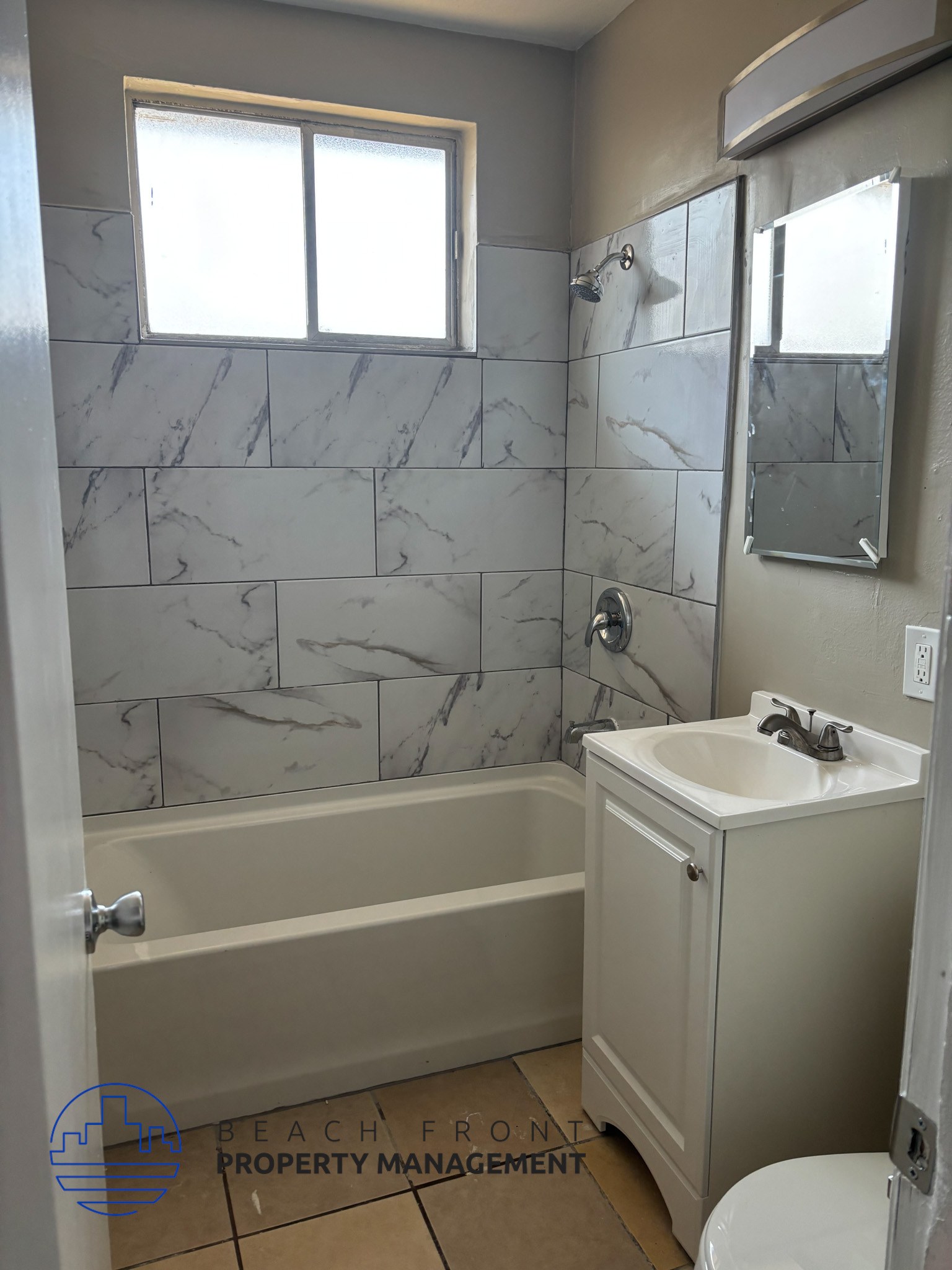 , A bathroom with a marble tile wall and a white sink.,A bathroom with a marble tile wall and a white sink.